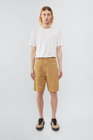 Model wearing Deadwood knee-length suede board shorts in the color mimosa. Hook and zipper closure and right back pocket. Made from recycled suede.