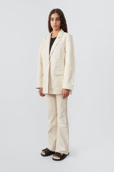 Model wearing Deadwood leather blazer in the color off-white. A beautiful oversized fit with single-button closure. Sizing runs big as this is an oversize fit. Made from recycled lambskin leather.