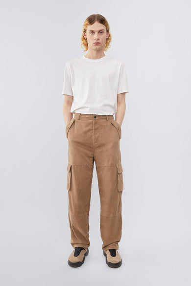 Model wearing Deadwood straight cut cargo pants with slightly dropped crotch, zip fly and workwear-inspired double waist pockets and leg pockets. One 32” length fits all. In color sand.  Made from recycled suede. 