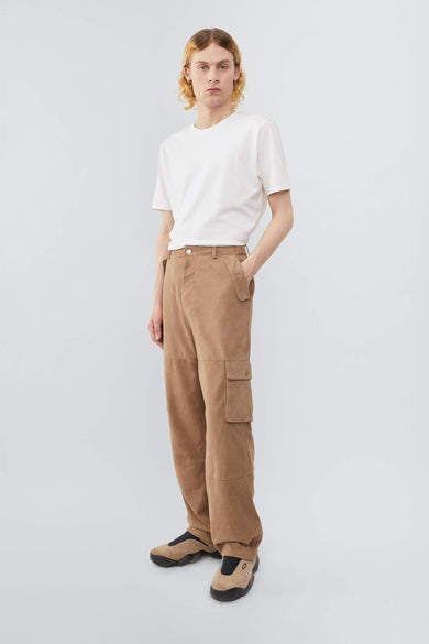 Model wearing Deadwood straight cut cargo pants with slightly dropped crotch, zip fly and workwear-inspired double waist pockets and leg pockets. One 32” length fits all. In color sand.  Made from recycled suede. 