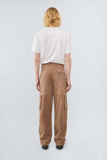 Model wearing Deadwood straight cut cargo pants with slightly dropped crotch, zip fly and workwear-inspired double waist pockets and leg pockets. One 32” length fits all. In color sand.  Made from recycled suede. 