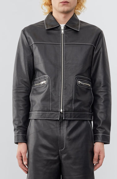 Model wearing  a straight-cut leather Deadwood jacket that echoes both 60's and 90's aesthetics. Black with white stitching all around. Made from upcycled leather.