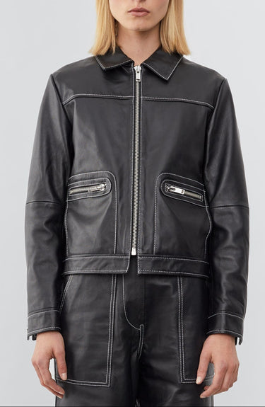 Model wearing a straight-cut leather Deadwood jacket that echoes both 60's and 90's aesthetics. Black with white stitching all around. Made from upcycled leather.