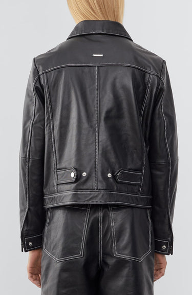 Model wearing a straight-cut leather Deadwood jacket that echoes both 60's and 90's aesthetics. Black with white stitching all around. Made from upcycled leather.