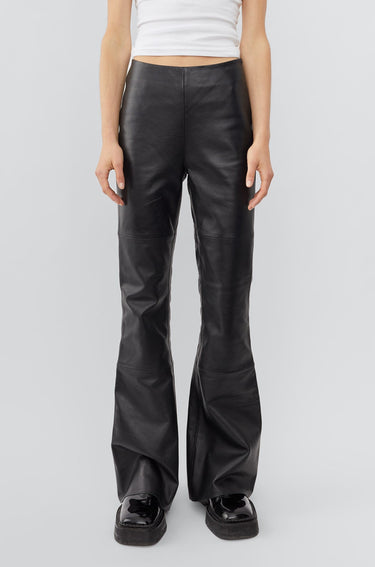 Model in black leather Kick Pants by Deadwood, slim-fit Y2K kick-flare with sustainable recycled materials.
