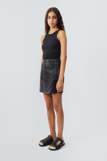 Model in side profile wearing black Lena recycled leather mini skirt by Deadwood, above-knee length 