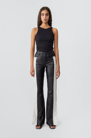 Model in Prance Black and White Leather Pants by Deadwood, featuring white stripes, bootcut fit, and slits at the leg opening, made from soft upcycled lambskin.