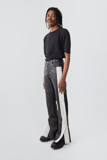 Model in Prance Leather Pants in black with white stripes and slits at leg opening, made from upcycled lambskin.