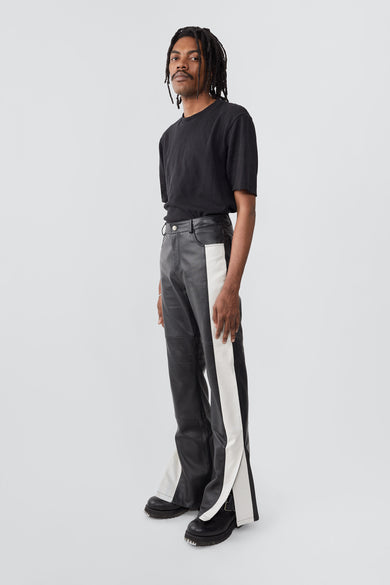 Model in Prance Leather Pants in black with white stripes and slits at leg opening, made from upcycled lambskin.