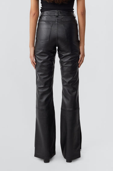 Model from the back in Prance Black and White Leather Pants by Deadwood, featuring white stripes, bootcut fit, and slits at the leg opening, made from soft upcycled lambskin.