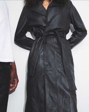 Girl wearing Terra recycled leather trench coat in black by Deadwood, classic silhouette with a tie belt.